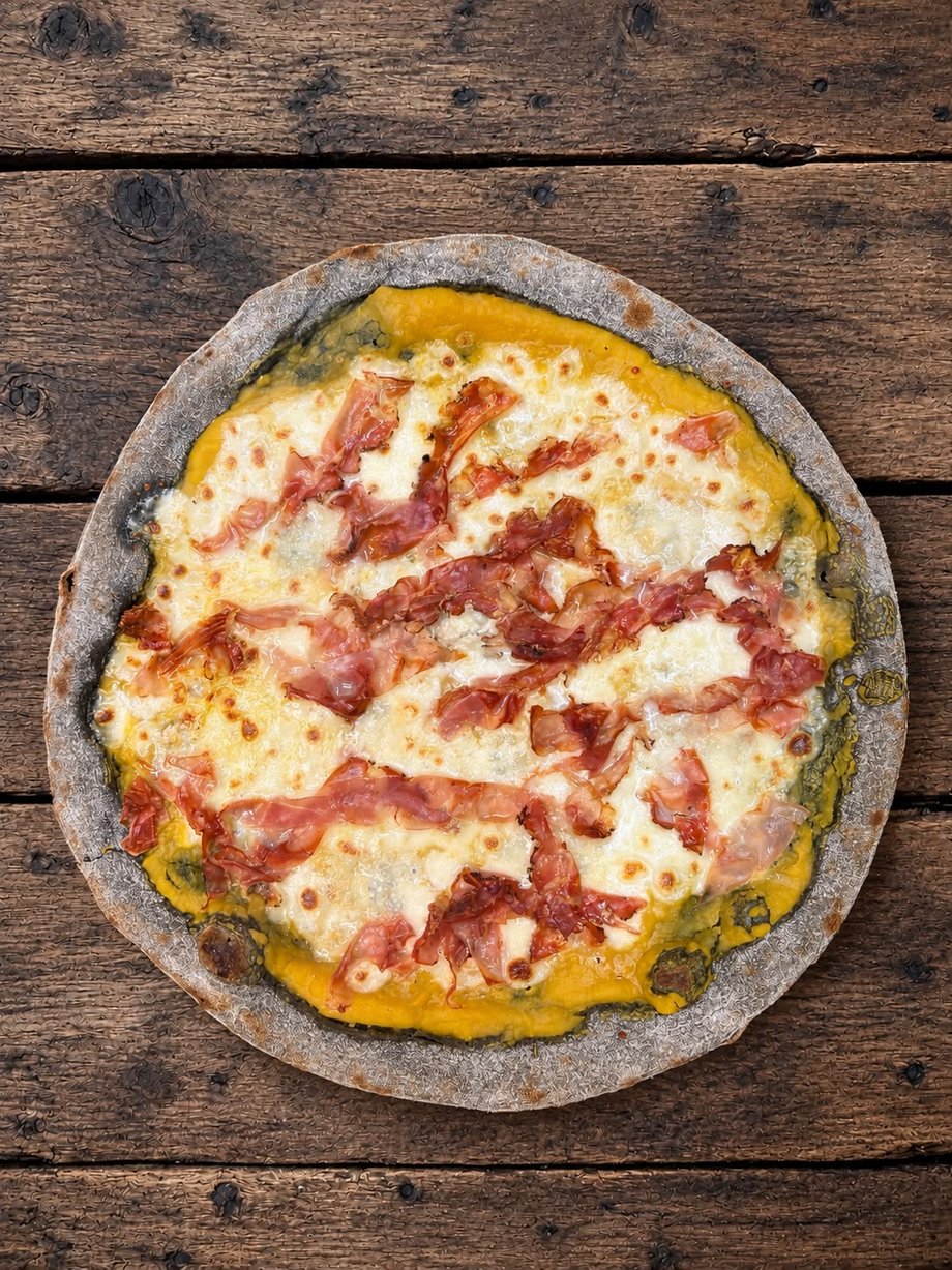 La pizza del mese di El Filò: impasto al carbone vegetale, crema di zucca, gorgonzola e speck croccante